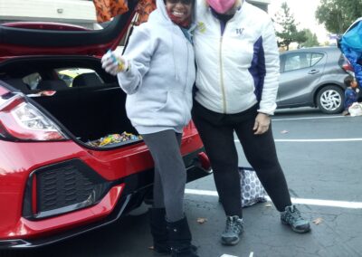 Two Local 8 members pose in front of a a car trunk with candy